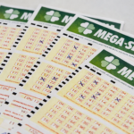 Vários volantes da Mega-Sena dispostos sobre superfície clara, com números marcados em caneta azul para participação no sorteio