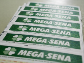 Vários bilhetes da Mega-Sena alinhados sobre superfície clara, em close-up com destaque para o logotipo verde da loteria