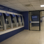 Pessoas realizando saques e depósitos em caixas eletrônicos dentro de agência bancária no Brasil