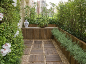 Pequeno jardim em varanda com parede verde, vasos e piso de madeira, exemplo de paisagismo para espaços reduzidos em apartamento.