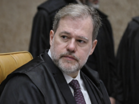 Ministro Dias Toffoli em sessão do STF, usando toga preta e gravata vinho, sentado em plenário com outros magistrados ao fundo.