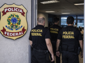 Agentes da Polícia Federal entram em prédio oficial durante operação sobre vazamento de dados da Receita Federal, com brasão da corporação na fachada.