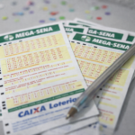 Volantes da Mega-Sena com caneta apoiada e confetes ao fundo, representando apostas em período festivo