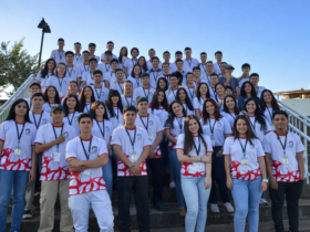 Grupo de jovens do projeto Trilha Jovem reunido em escadaria ao ar livre em Foz do Iguaçu após conquista de prêmio internacional