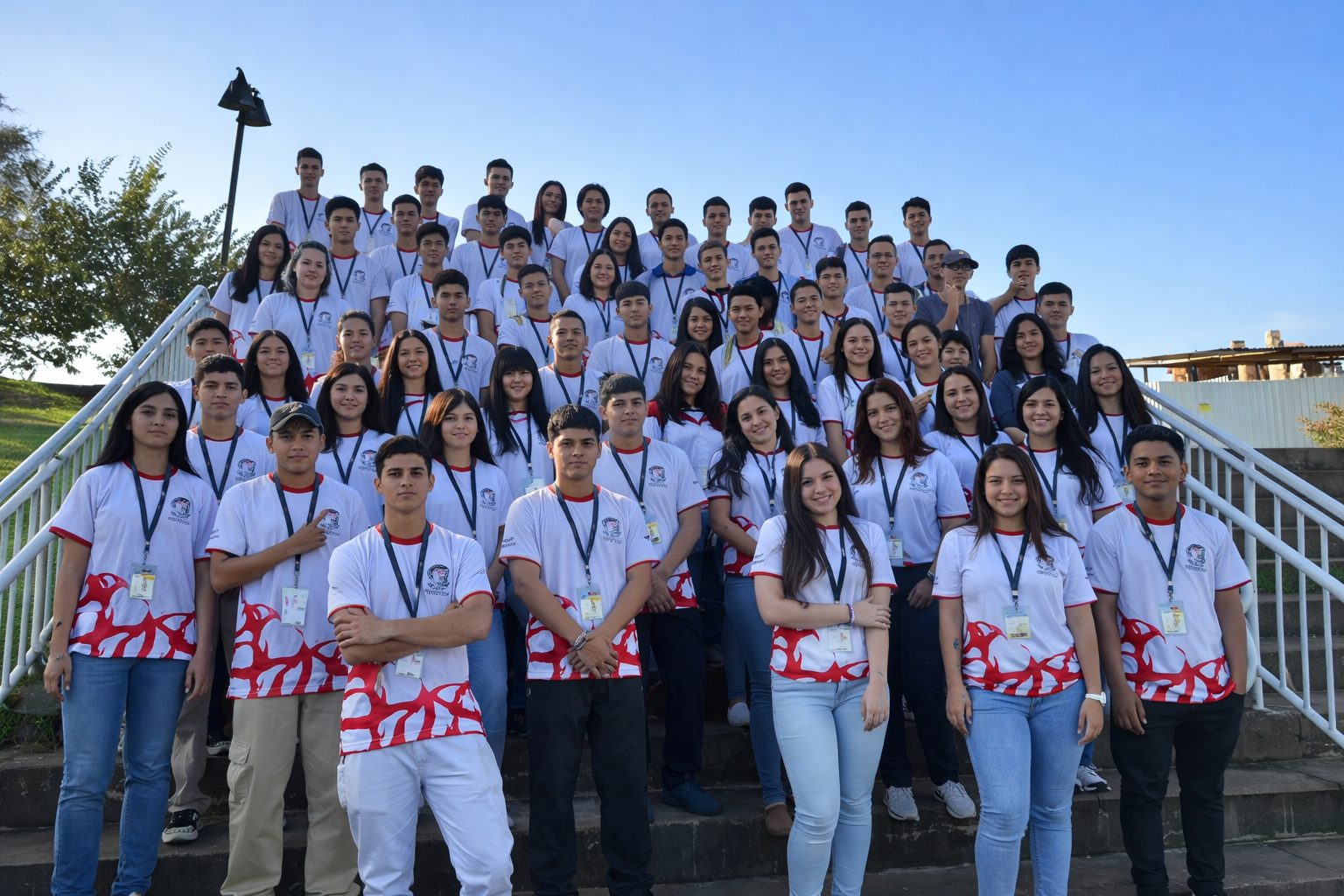 Grupo de jovens do projeto Trilha Jovem reunido em escadaria ao ar livre em Foz do Iguaçu após conquista de prêmio internacional
