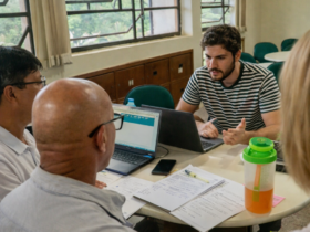 Professores e gestores reunidos em sala com notebook e documentos discutindo conectividade em escola rural do Distrito Federal