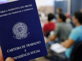 Carteira de Trabalho e Previdência Social em primeiro plano com trabalhadores desfocados ao fundo, representando debate sobre jornada de trabalho no Brasil