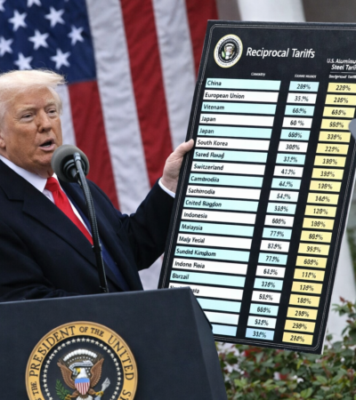 Autoridade norte-americana apresenta painel com tarifas sobre aço e alumínio diante da bandeira dos Estados Unidos, simbolizando política comercial dos EUA