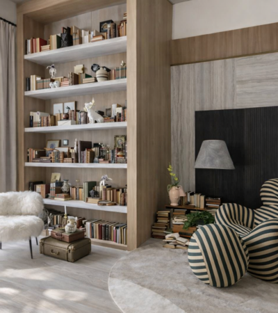 Biblioteca em casa com estante de livros, poltrona listrada e iluminação suave criando espaço acolhedor para leitura