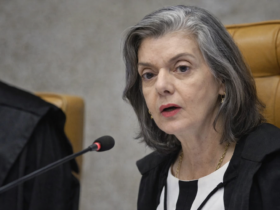 Cármen Lúcia fala ao microfone em sessão do TSE, sentada em cadeira do plenário com toga preta
