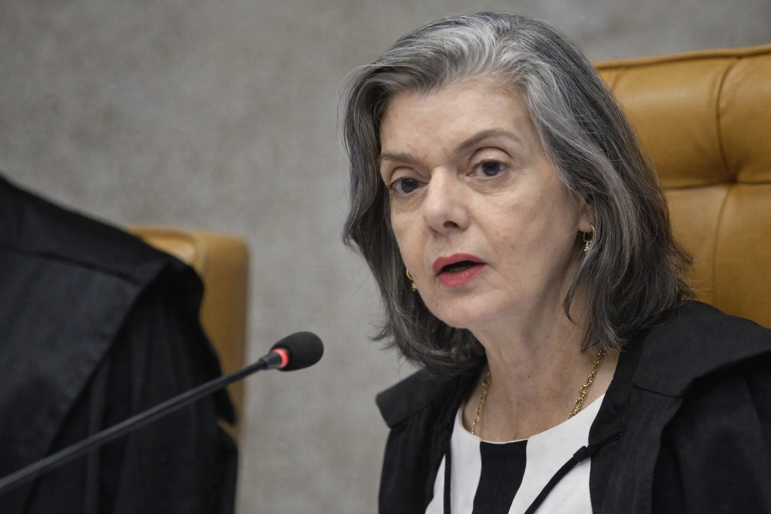 Cármen Lúcia fala ao microfone em sessão do TSE, sentada em cadeira do plenário com toga preta