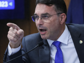 Flávio Bolsonaro fala ao microfone durante sessão no Senado, usando terno escuro e gravata azul em plenário oficial