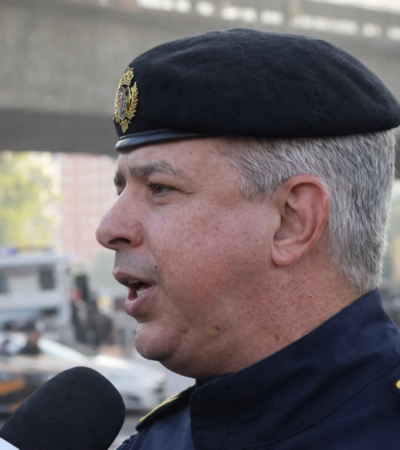 Oficial da Polícia Militar do Rio de Janeiro fala à imprensa sobre o balanço do Carnaval, usando uniforme e boina em área urbana