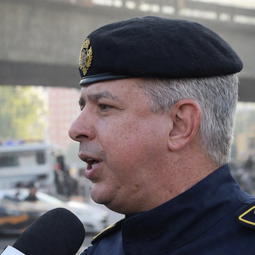 Oficial da Polícia Militar do Rio de Janeiro fala à imprensa sobre o balanço do Carnaval, usando uniforme e boina em área urbana