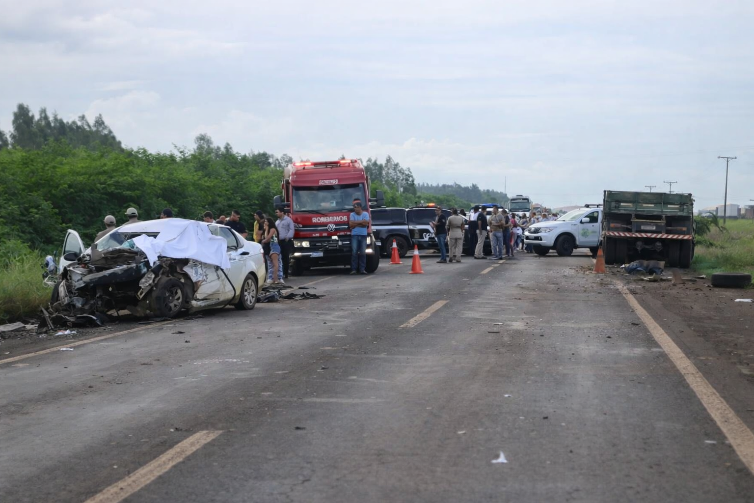 Cena de colisão entre carro e caminhão na BR-463 com viaturas do Corpo de Bombeiros e polícia atendendo ocorrência em rodovia rural
