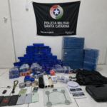 Tabletes de maconha, balanças de precisão, celulares e colete tático apreendidos pela Polícia Militar de Santa Catarina exibidos em sala oficial