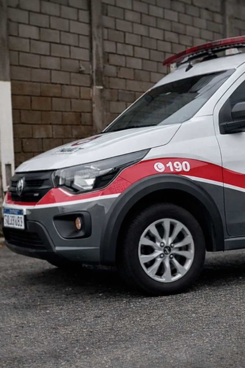 Viatura da Polícia Militar de São Paulo estacionada em área urbana, com faixa vermelha e número 190 visíveis na lateral