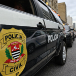 Viatura da Polícia Civil de São Paulo estacionada em rua urbana, com brasão oficial em destaque e outras viaturas ao fundo.