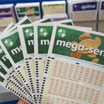 Cartelas da Mega-Sena abertas em leque em balcão de lotérica, com outros jogos ao fundo, representando apostas em prêmio milionário