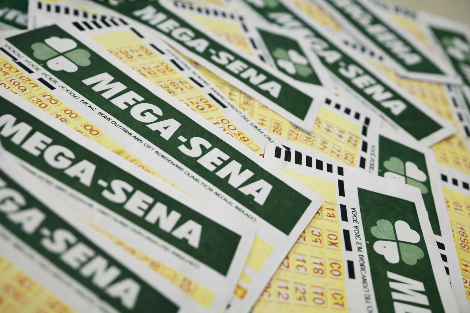 Cartões da Mega-Sena alinhados e sobrepostos, representando apostas em loteria e prêmio acumulado no Brasil