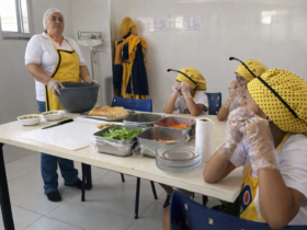 Crianças participando de oficina de preparo de alimentos em cozinha educativa de projeto social comunitário.